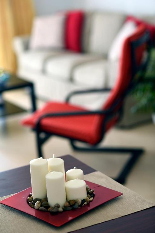 a tray of white candles on a table with a red chair at Casa Lola in Agaete