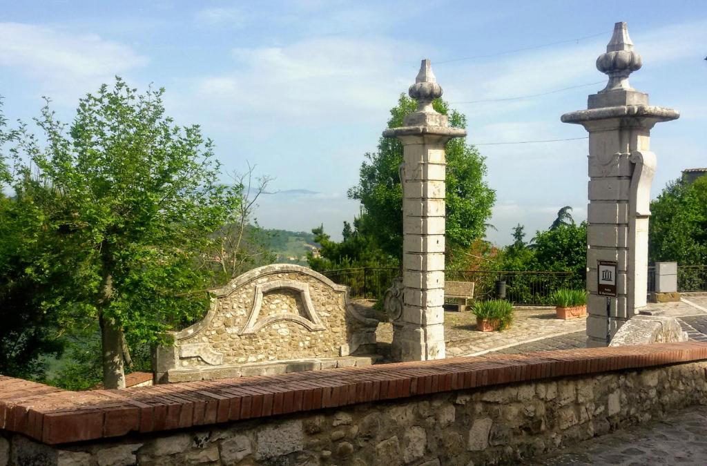 a stone wall with two towers in a garden at B&B Le Colonne in Montefusco