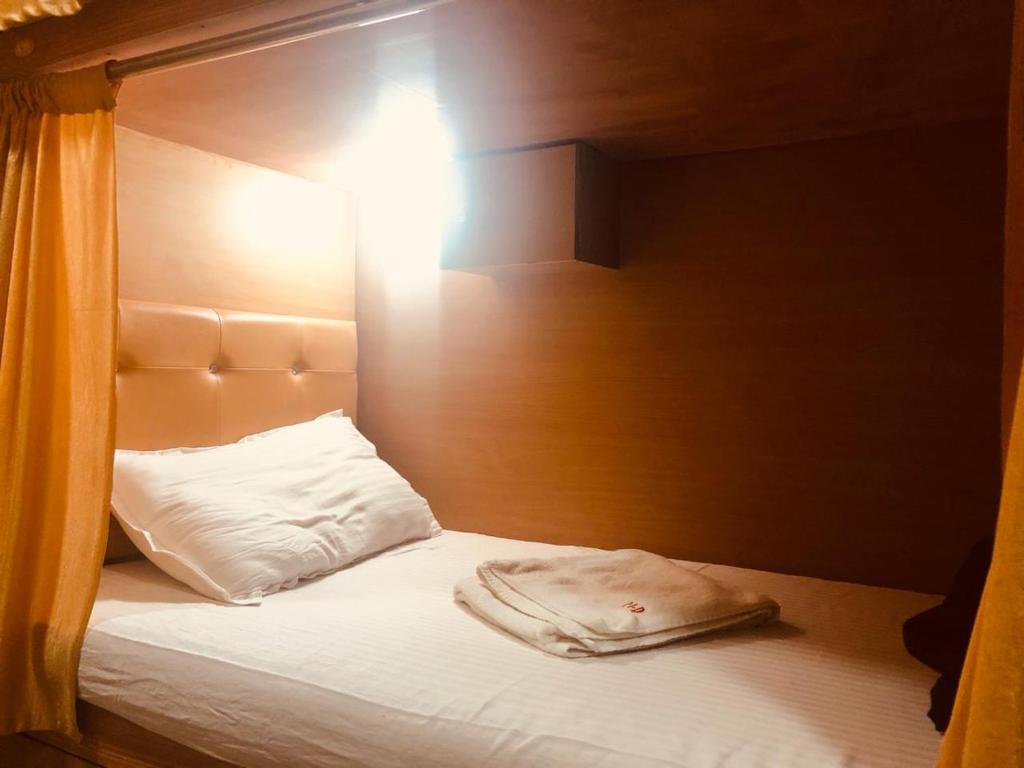 a bed with a wooden headboard and a white pillow at Mabrook Dormitory in Mumbai