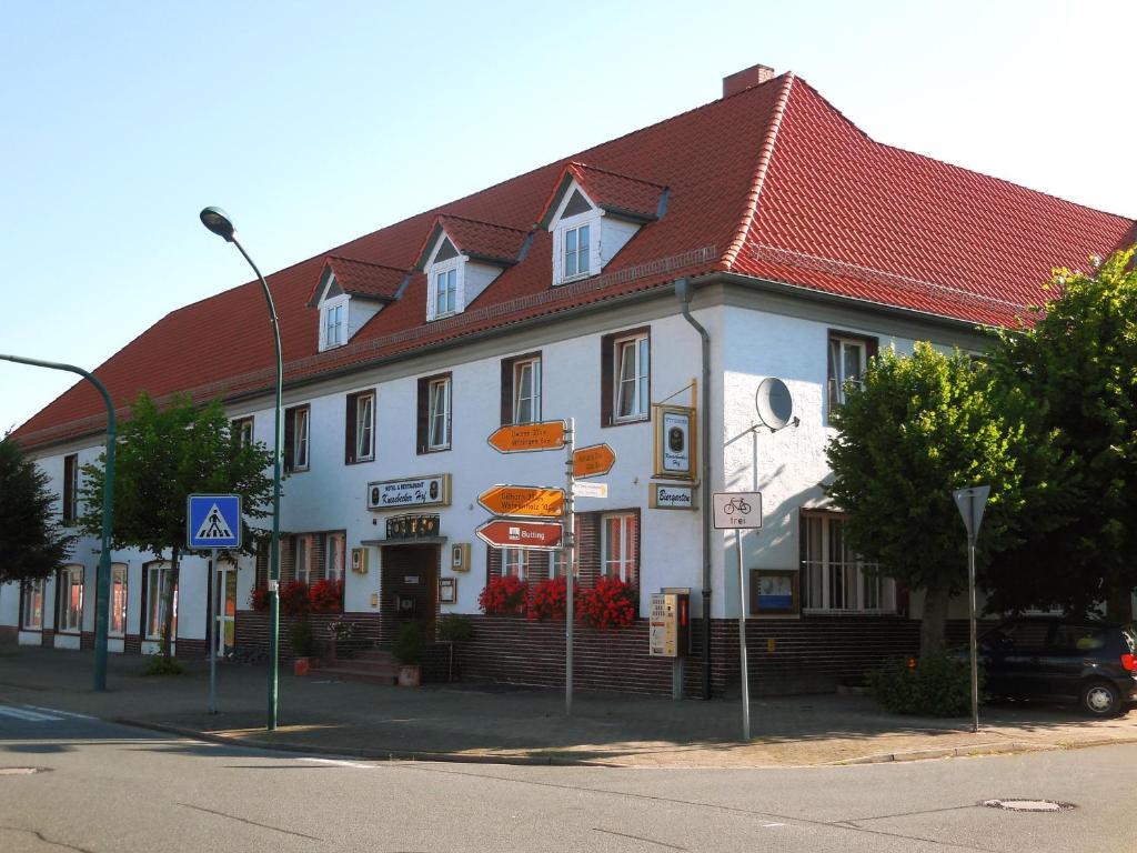 un bâtiment blanc avec un toit rouge dans une rue dans l'établissement Hotel und Restaurant Knesebecker Hof, à Knesebeck