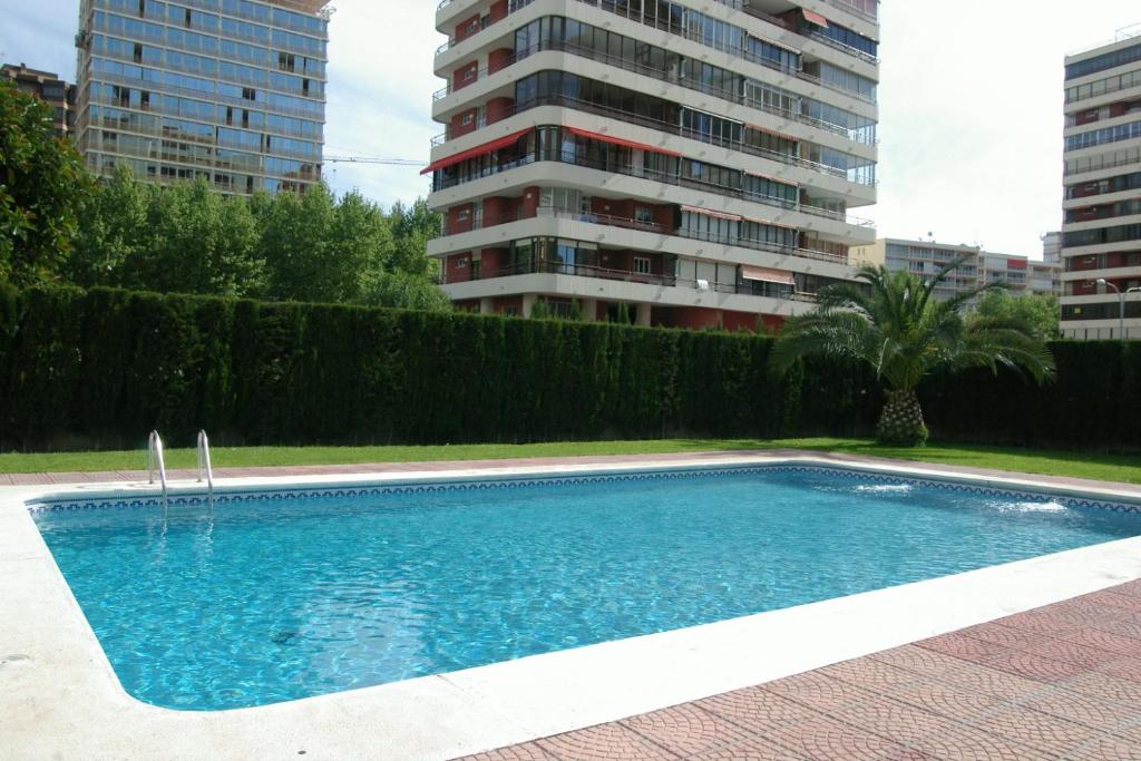a swimming pool in front of a tall building at Apartamentos Carolina - Arca Rent in Benidorm