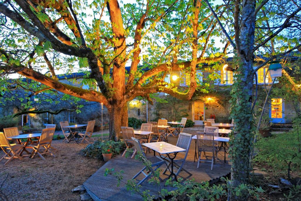 a group of tables and chairs under a tree at Hotel La Maison des Peyrat in Sarlat-la-Canéda