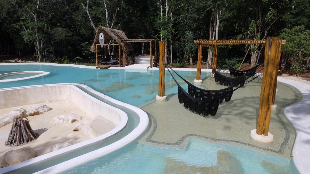 een zwembad met glijbaan en schommels bij Hotel Okaan in Chichén-Itzá