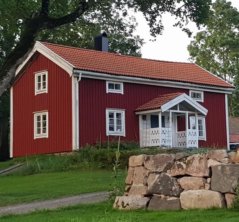 a red barn with white windows and a stone wall at 1800-tals torp i landsbygd nära till allt in Värnamo