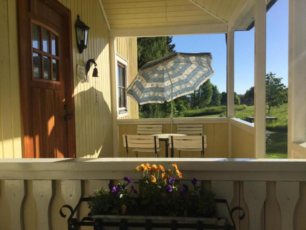 a porch with a bench and an umbrella on a house at Lilla Lilo Gården in Östersund