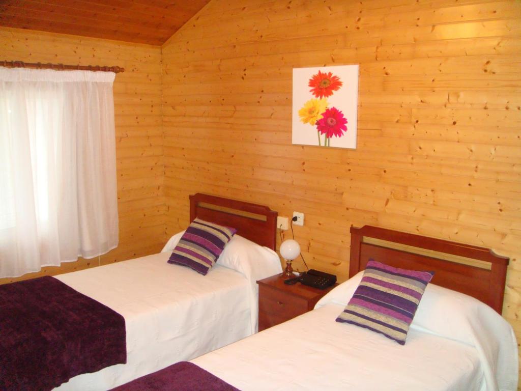 two beds in a room with wooden walls at Hotel Abrego Reinosa in Reinosa