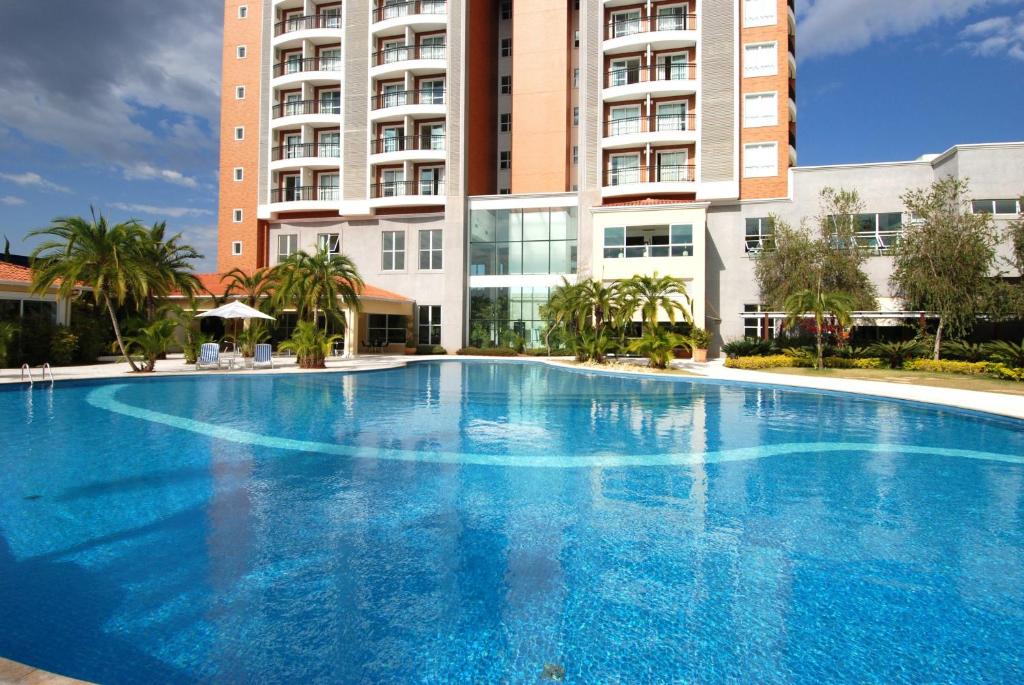 a large blue swimming pool in front of a building at Vitória Hotel Convention Indaiatuba in Indaiatuba