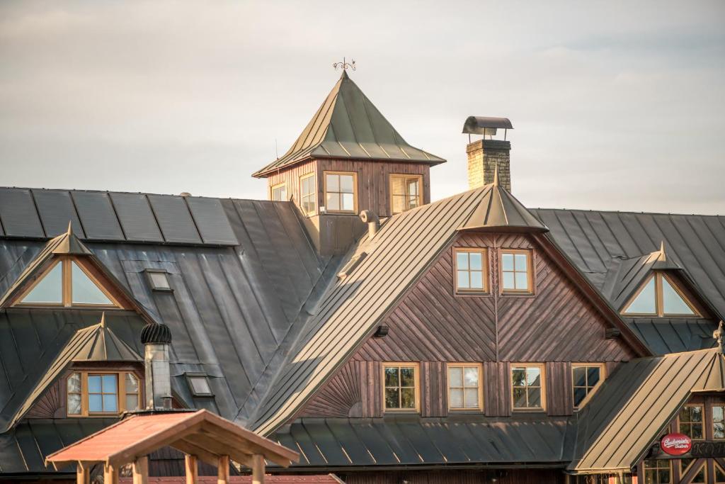 une grande maison en bois avec un toit en gambrel dans l'établissement Horský Hotel Kohútka, à Nový Hrozenkov