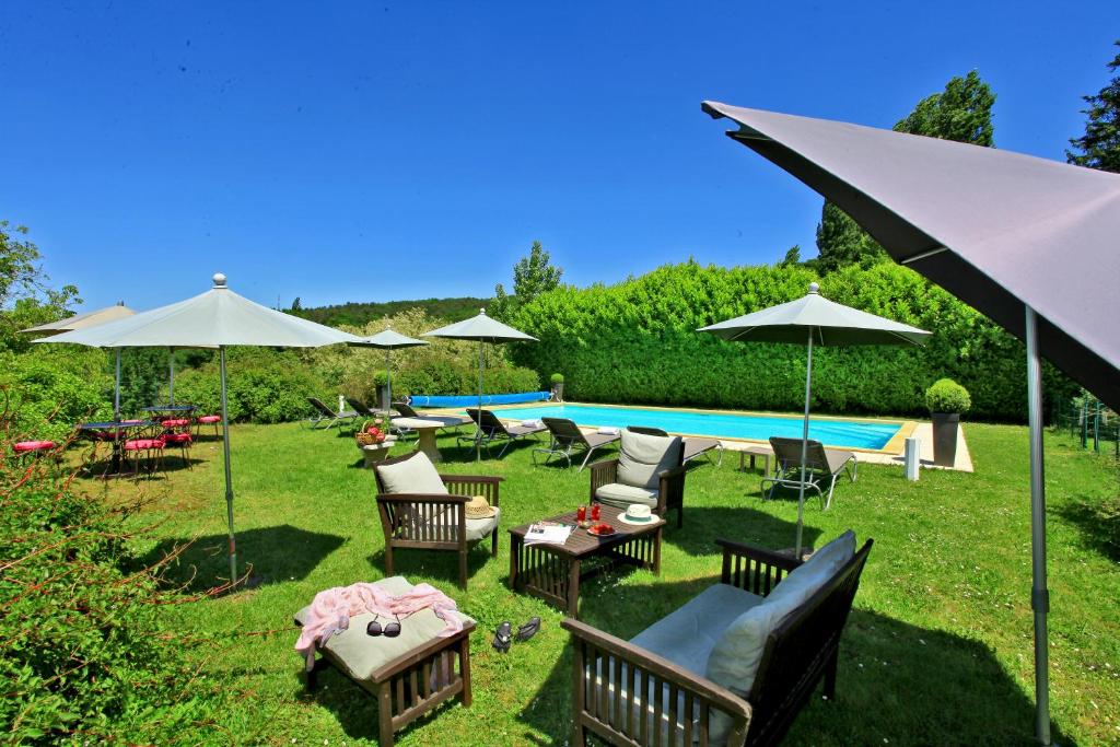 a yard with chairs and umbrellas and a pool at Hotel La Maison des Peyrat in Sarlat-la-Canéda