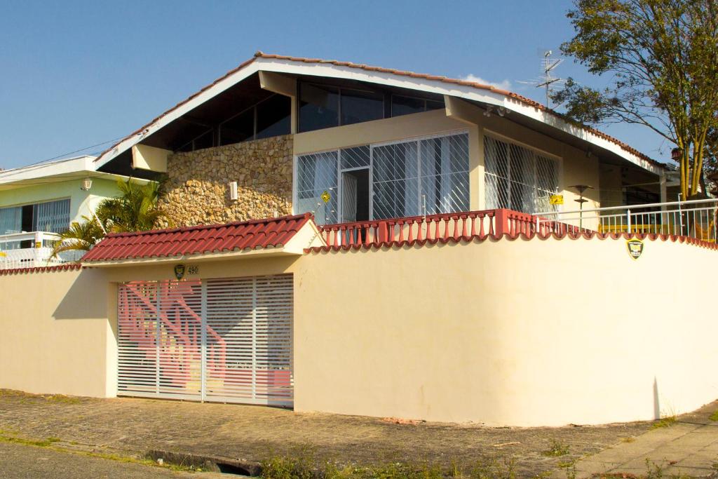 Uma casa branca com um portão à frente. em Bela Curitiba Hostel em Curitiba