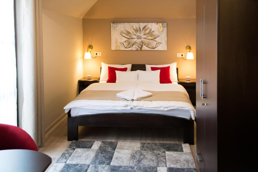 a bedroom with a large bed with red pillows at MeDoRa Park - Hotel MeDoRa*** in Gárdony