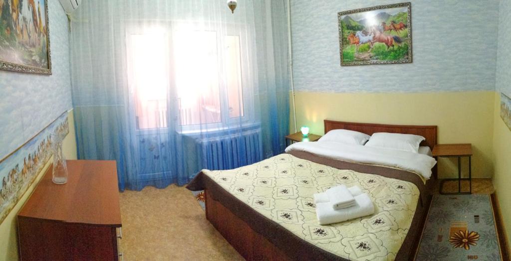 um quarto com uma cama, uma secretária e uma janela em Апартаменты на улице Розыбакиева, 275-2 em Almaty