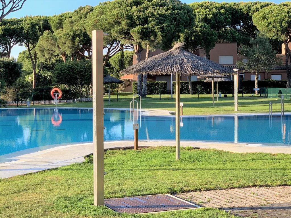 un complejo con piscina con sombrilla de paja en Novo Sancti Petri - Adosado Residencial El Trebol - Chiclana, en Chiclana de la Frontera