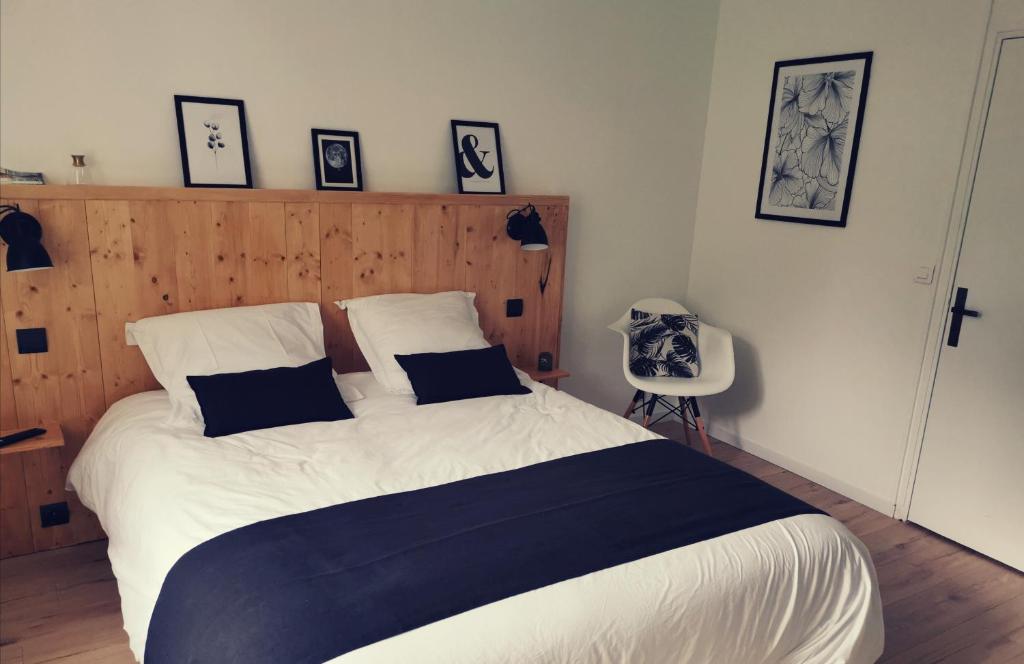 Schlafzimmer mit einem großen Bett mit einem Kopfteil aus Holz in der Unterkunft À tire-larigot in Cousances-aux-Forges