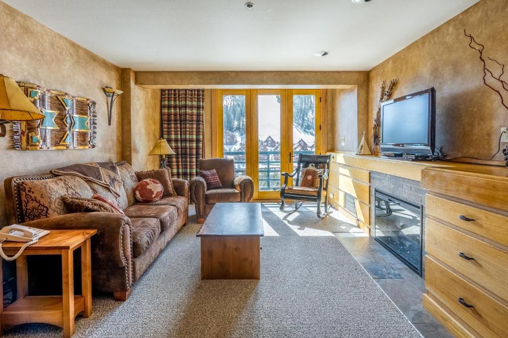 ein Wohnzimmer mit einem Sofa und einem TV in der Unterkunft Shoshone Condo 1950 in Big Sky
