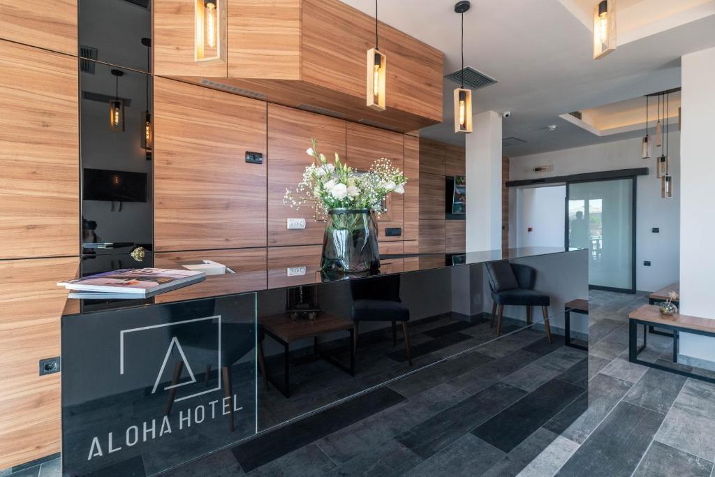 a lobby with a reception desk with a vase of flowers at Hotel Aloha in Niš