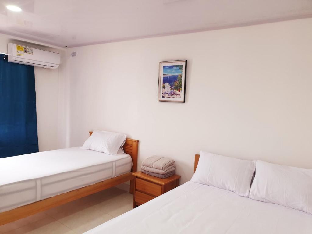 a bedroom with two beds and a picture on the wall at Alojamientos Laila Sai y Zaida in San Andrés