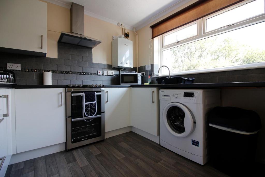 a kitchen with white cabinets and a washer and dryer at Hinckley Home Sleeps 5 Complete House in Leicester