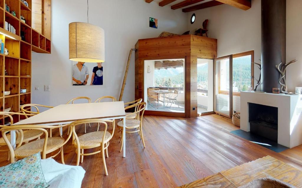 ein Esszimmer mit einem Tisch, Stühlen und einem Kamin in der Unterkunft Duos Sours in Celerina