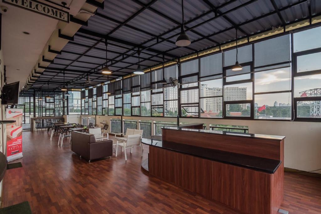 a large room with tables and chairs and windows at RedDoorz Plus near Semanggi in Jakarta