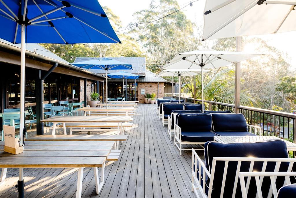 a patio area with tables, chairs and umbrellas at Avoca Beach Hotel in Avoca Beach