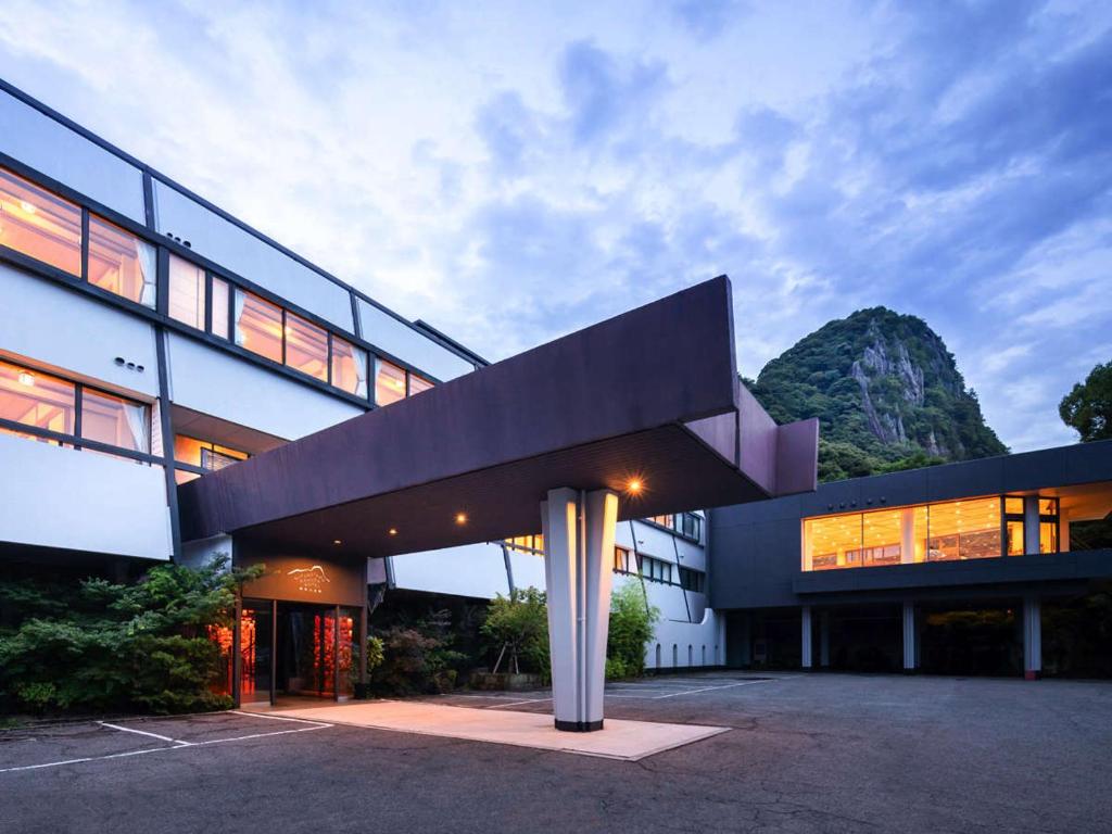 a large building with a mountain in the background at Mifuneyama Rakuen Hotel in Takeo