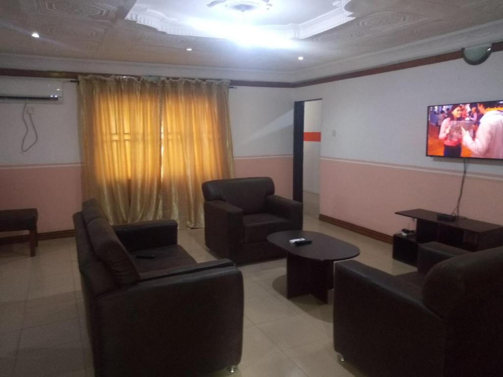 a waiting room with couches and a flat screen tv at Tiffany Apartments in Ibadan