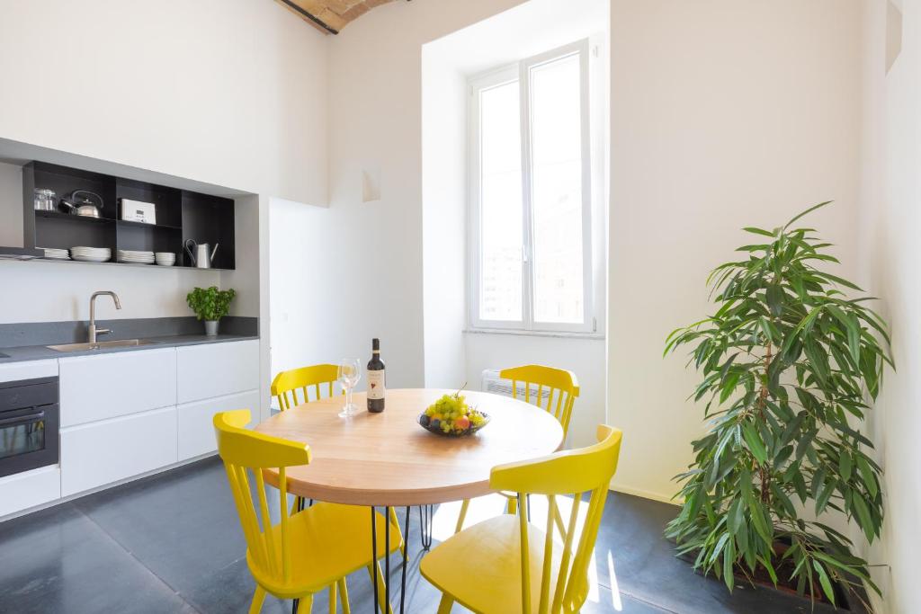 eine Küche mit einem Holztisch und gelben Stühlen in der Unterkunft Mini appartamento Colosseo in Rom