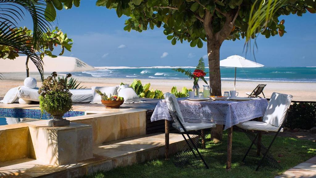 uma mesa e cadeiras junto à praia em Casa de Areia em Jericoacoara