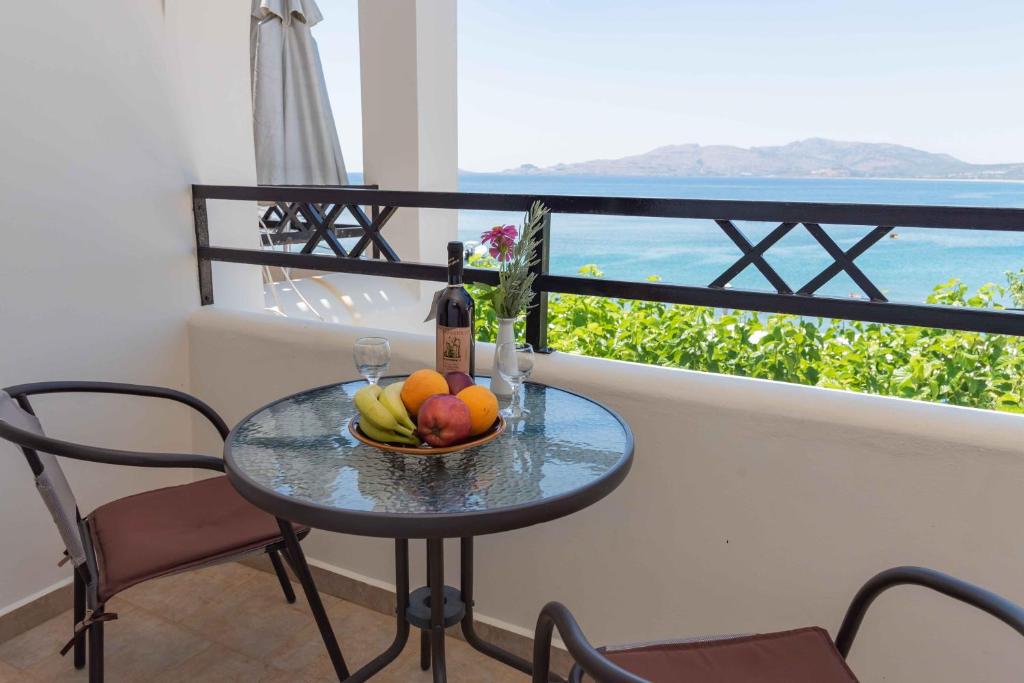 een tafel met een fruitschaal en een fles wijn bij Haraki Sand Beach in Charaki