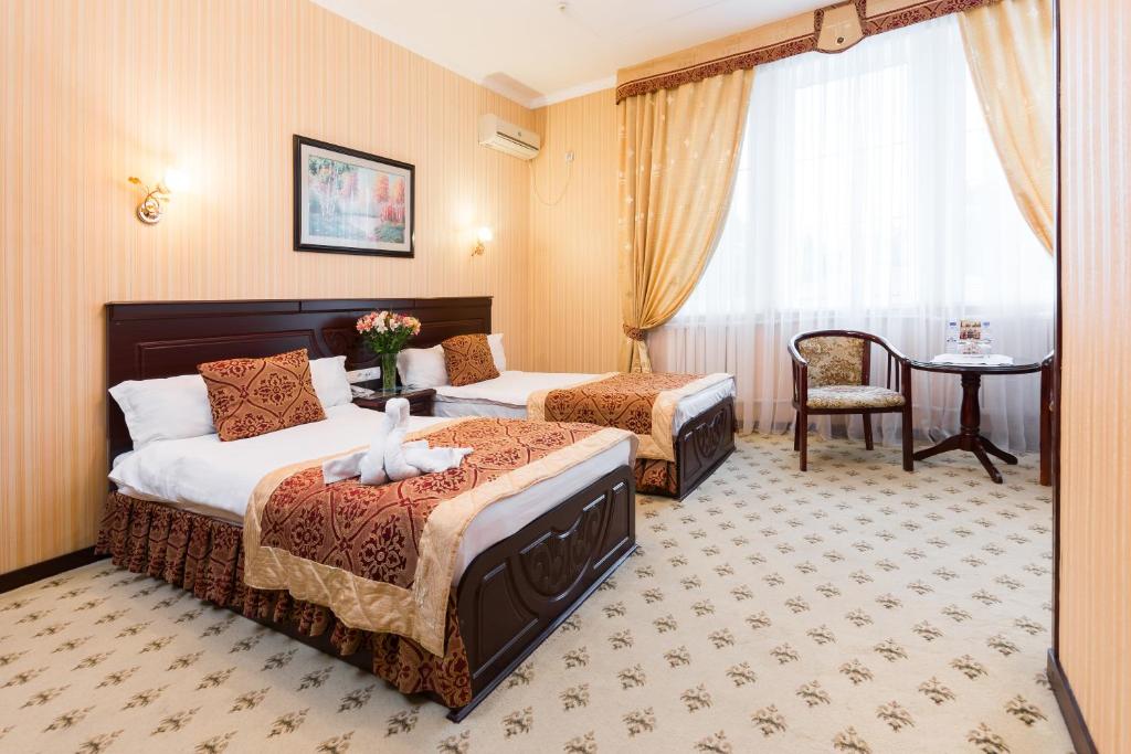 a hotel room with two beds and a table at Asia Hotel Fergana in Fergana