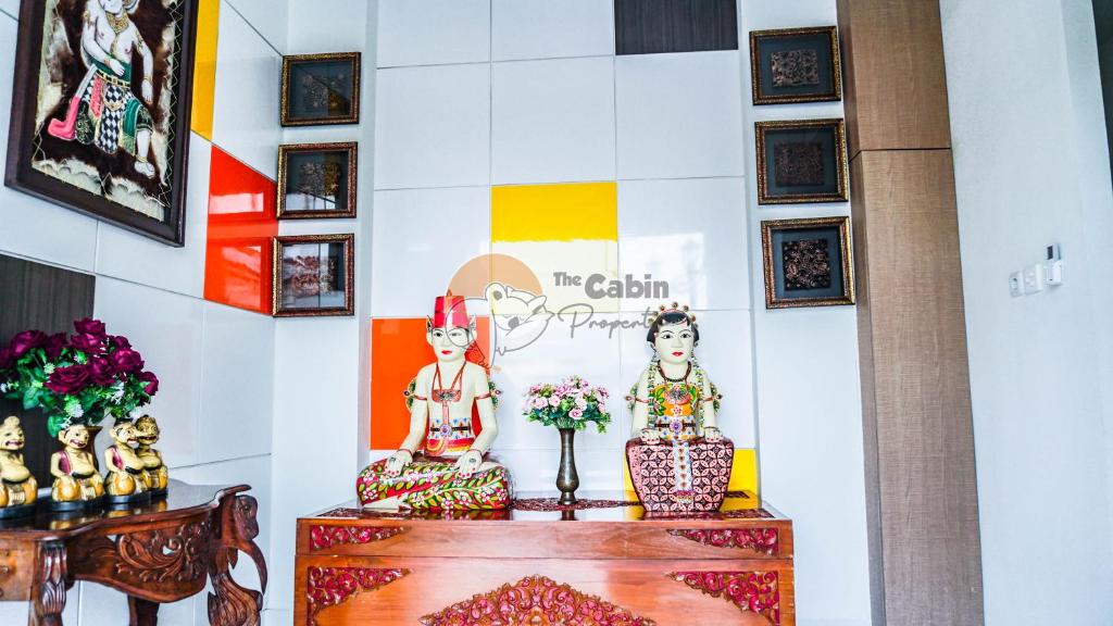 a room with two statues and a wall with pictures at The Cabin Tugu Hostel in Yogyakarta