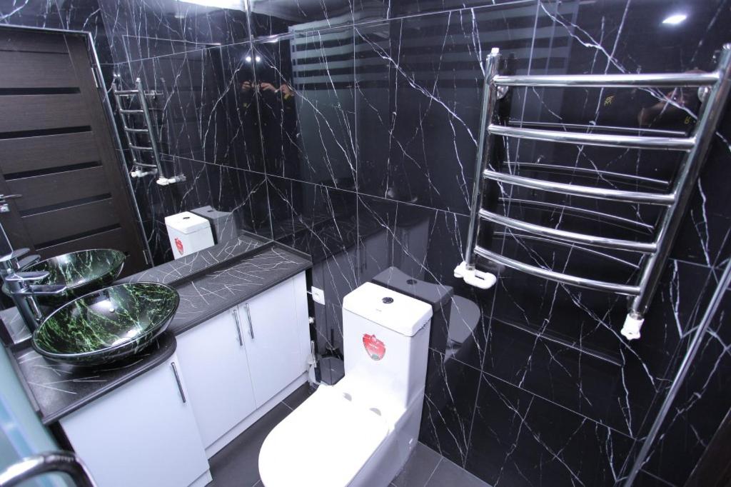 baño con aseo y pared de azulejos negros en Overlooking Registan Square Luxury 2 Bedrooms Apartment en Samarcanda