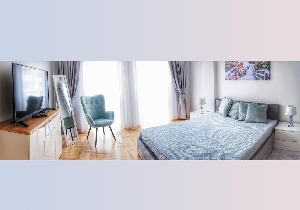 sypialnia z łóżkiem, telewizorem i krzesłem w obiekcie AMN APARTMENTS w Warszawie