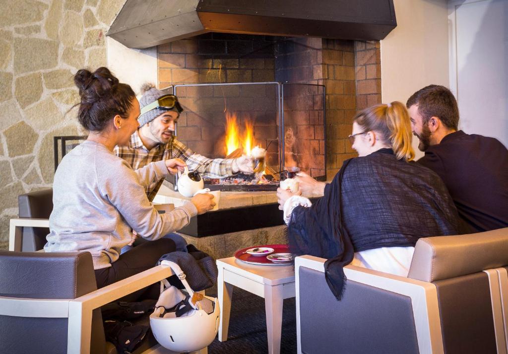 a group of people sitting around a fireplace at Hôtel Club mmv Les Bergers **** in L'Alpe-d'Huez