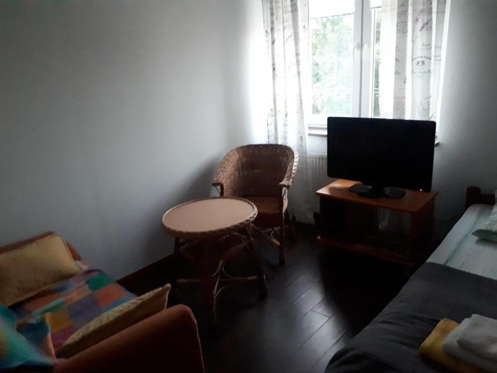 a living room with a tv and a table and chairs at Kwatera Jolanta in Ełk