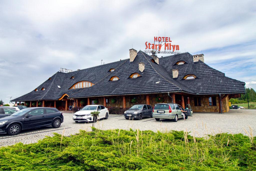 a large building with cars parked in a parking lot at Hotel Stary Młyn in Koziegłowy