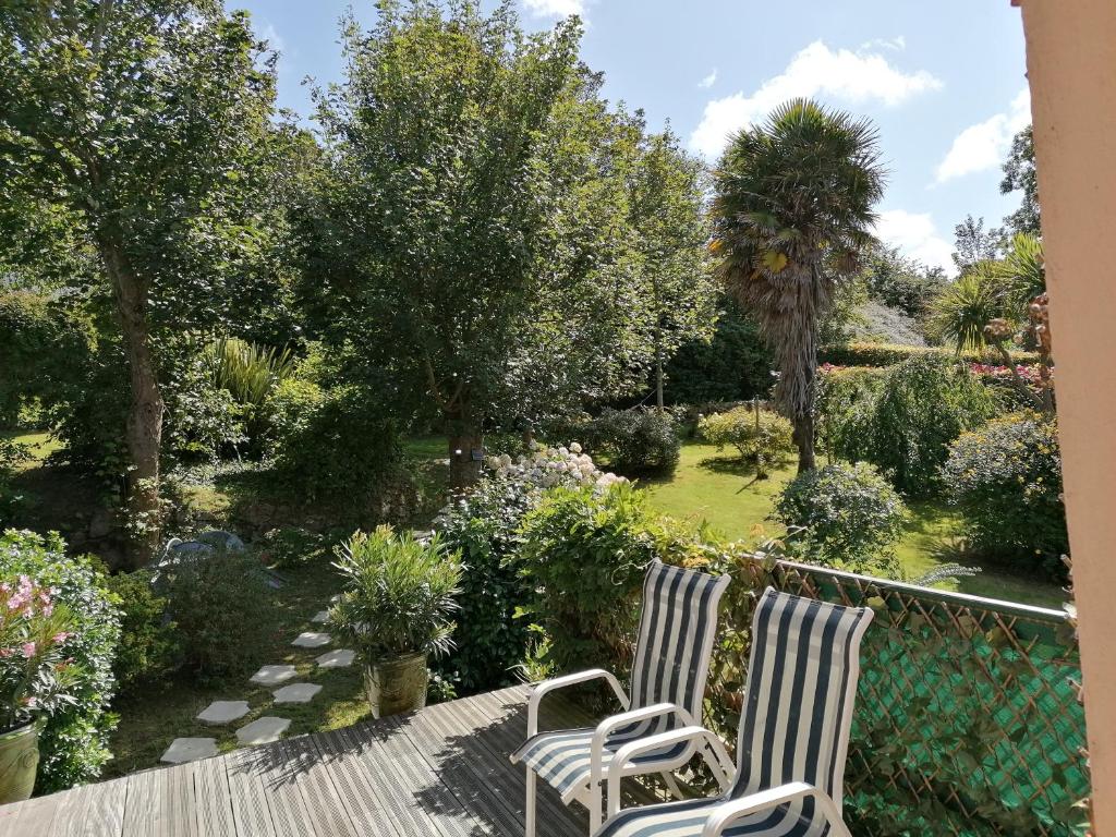 2 chaises assises sur une terrasse dans un jardin dans l'établissement logement en campagne, à Landemer