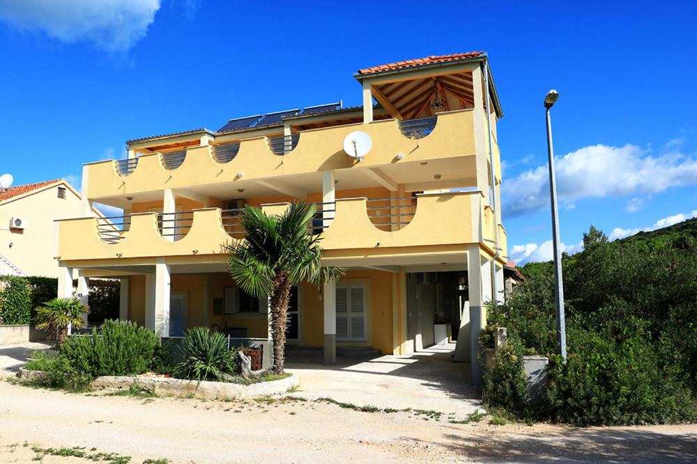 żółty budynek z palmą przed nim w obiekcie G.Baković w mieście Jezera