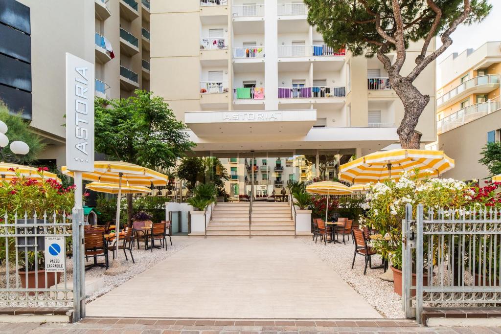 a building with tables and chairs and umbrellas at Hotel Astoria in Cattolica