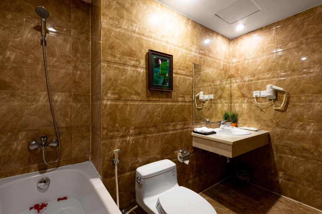 La salle de bains est pourvue de toilettes, d'un lavabo et d'une baignoire. dans l'établissement First Eden Hotel - Hang Bun, à Hanoï