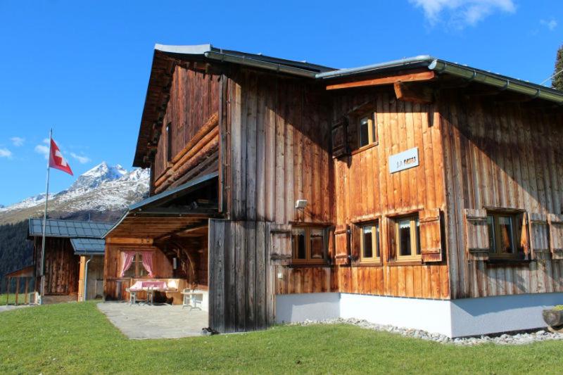 a large wooden building with a mountain in the background at La Casa Cathomen Brigels - Maiensäss/Berghaus für max. 6 Personen in Breil/Brigels