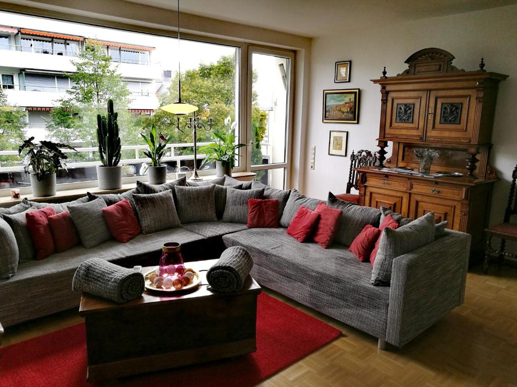 ein Wohnzimmer mit einem grauen Sofa und roten Kissen in der Unterkunft LUXURIÖSE FERIENWOHNUNG CONFLUENTIA IN DER KOBLENZER ALTSTADT in Koblenz