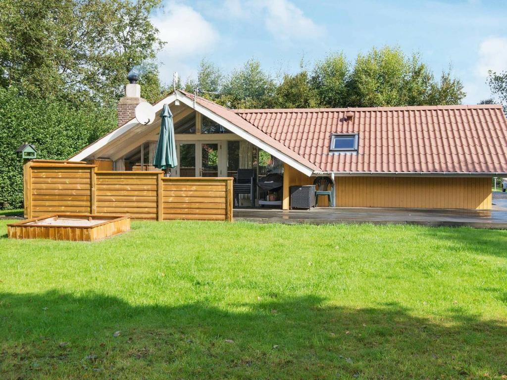 a house with a wooden fence and a umbrella at 6 person holiday home in Hemmet in Falen