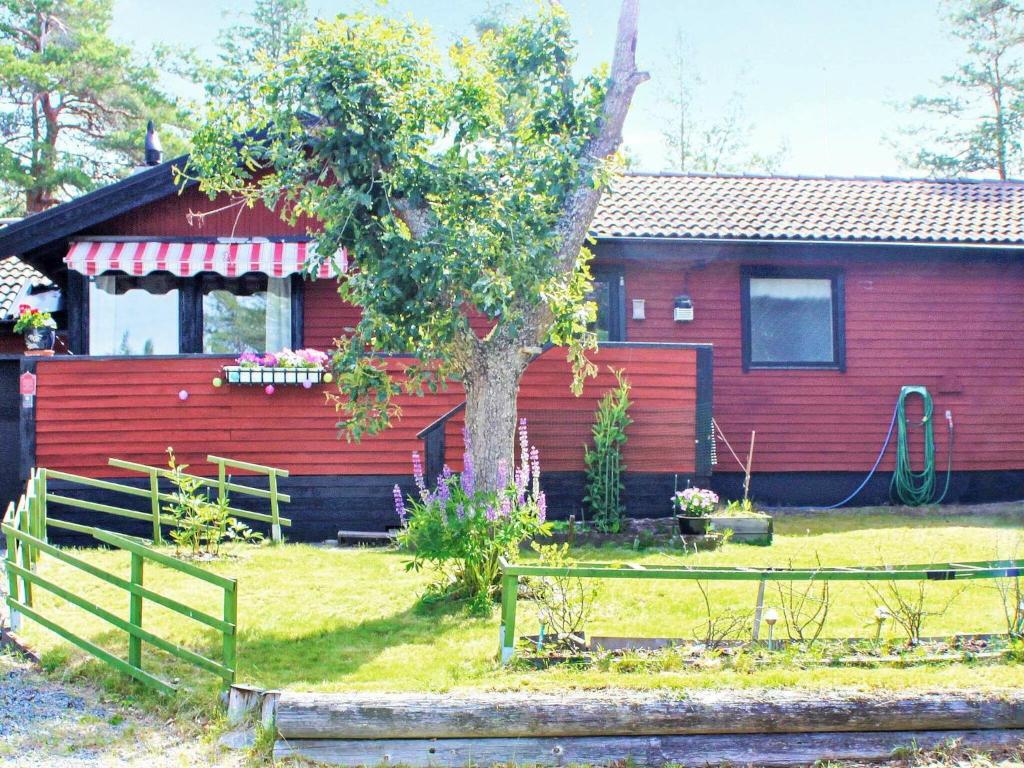 una casa roja con un árbol delante en 7 person holiday home in LIDK PING en Lidköping