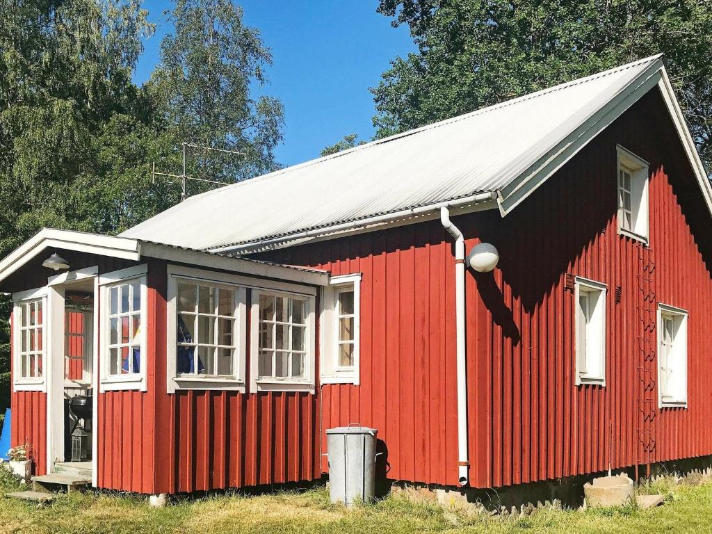 un granero rojo con techo blanco y ventanas en 6 person holiday home in VARA, en Skår