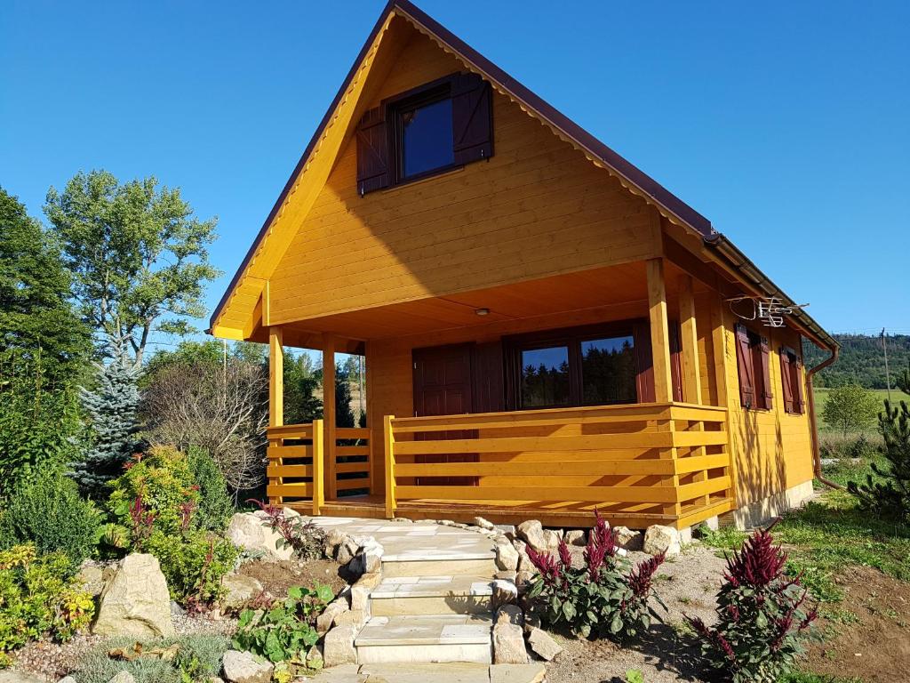 une grande cabane en bois avec une passerelle en face de celle-ci dans l'établissement Domki całoroczne z kominkiem - SKAŁA i GŁAZ, à Szczytna