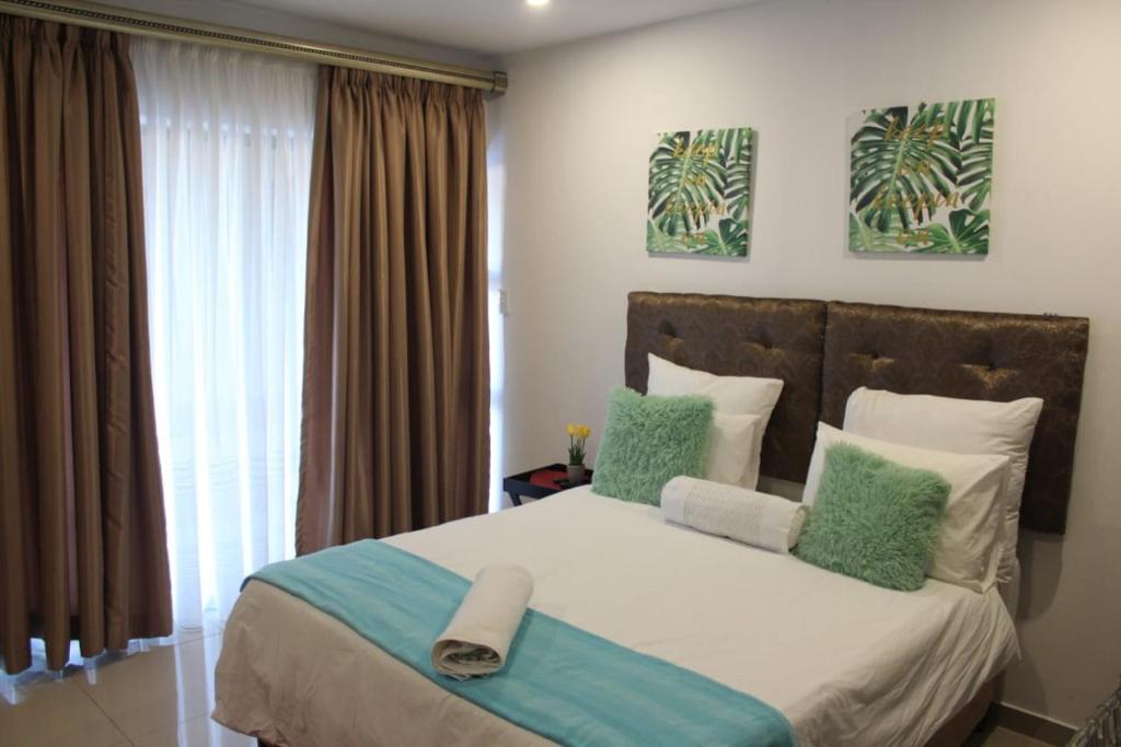 una camera da letto con un grande letto con cuscini verdi e bianchi di M-crystals a Richards Bay