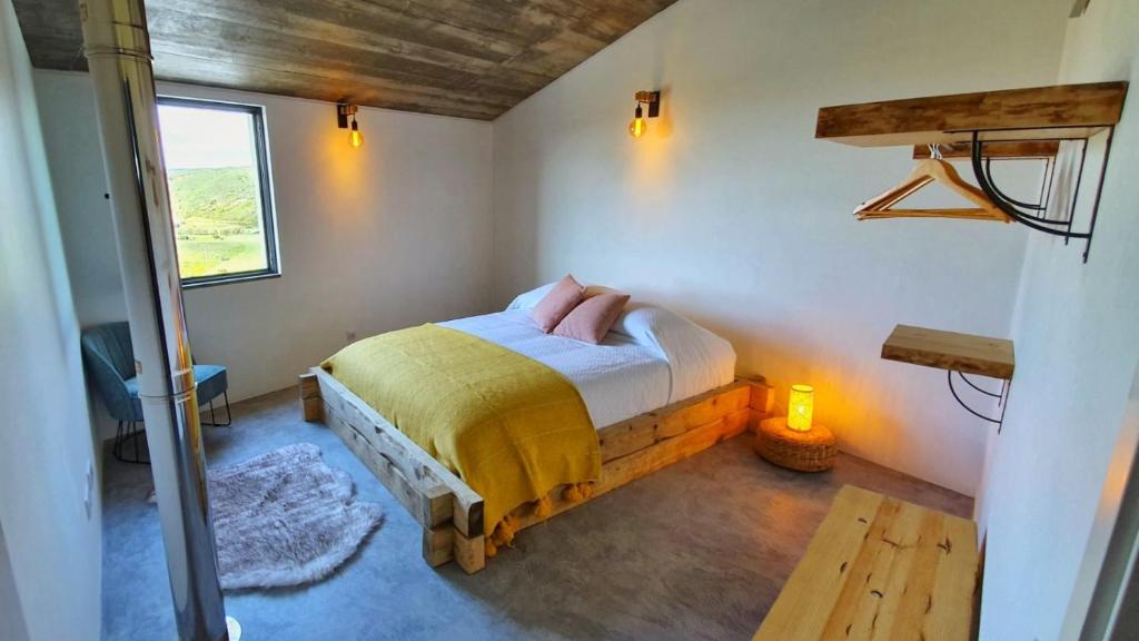 1 dormitorio con 1 cama en una habitación con ventana en Casa Bombordo, en Carrapateira