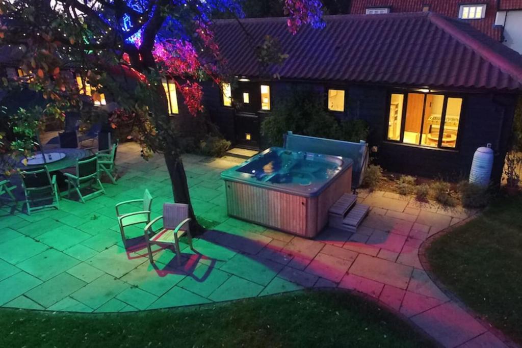 a backyard with a hot tub and a table and chairs at Priory Farm Barn in Eye